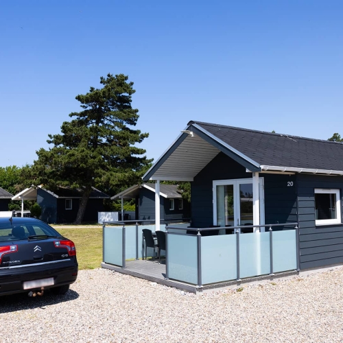 30m2 hytte set udefra med parkeringsplads til bilen på Storebælt Camping