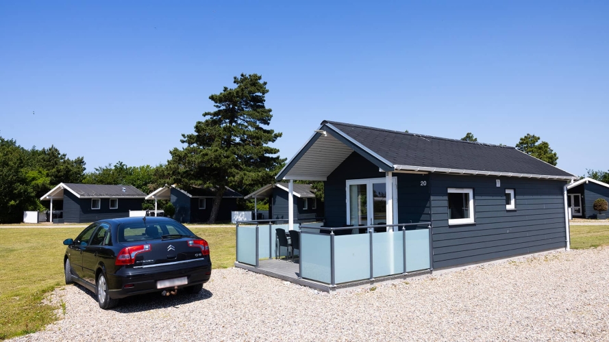 30m2 hytte set udefra med parkeringsplads til bilen på Storebælt Camping