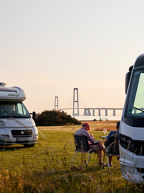 Autocampere nyder aftensolen med flot udsigt til Storebæltsbroen på Storebælt Camping-